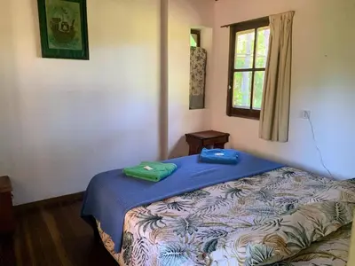 a bedroom with a bed with blue sheets and a window at Casita de campo in Villa Ciudad Parque