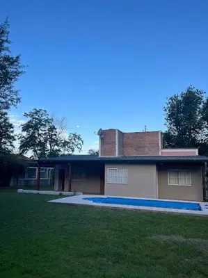 a house with a grass yard in front of it at Cabañas El Chañar in Villa Santa Cruz del Lago