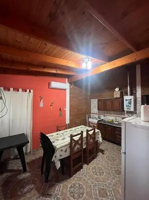 a kitchen with a table and a kitchen with a refrigerator at Cabañas El Chañar in Villa Santa Cruz del Lago