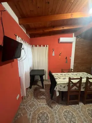 a dining room with a table and a tv in a room at Cabañas El Chañar in Villa Santa Cruz del Lago