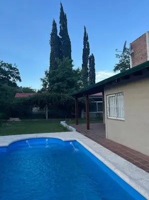 a large blue swimming pool next to a house at Cabañas El Chañar in Villa Santa Cruz del Lago
