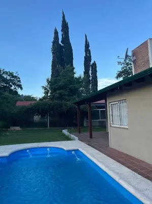 a large blue swimming pool next to a house at Cabañas El Chañar in Villa Santa Cruz del Lago