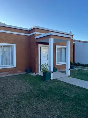 a brick house with a white door and a grass yard at Luna Vallista House in Mina Clavero