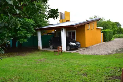 a car parked outside of a small yellow house at Sierras Del Molle in Santa Rosa de Calamuchita
