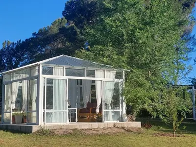 a conservatory in a field with a tree at Bosquemolinos in Villa Los Molinos