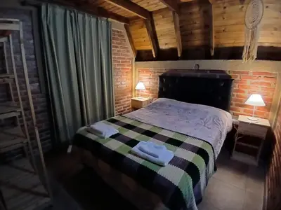 a bedroom with a bed with two lamps on two tables at Cabañas y departamentos Sol y Luna in Villa General Belgrano
