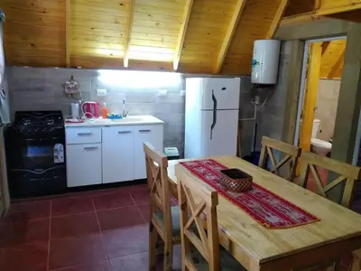a kitchen with a table and a white refrigerator at Cabañas y departamentos Sol y Luna in Villa General Belgrano
