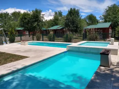 a swimming pool with a house in the background at Cabañas Esmeralda in Villa Ciudad de America