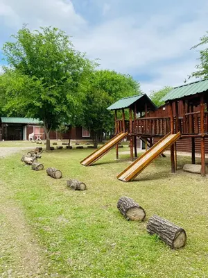 a playground with a slide and logs in the grass at Cabañas Esmeralda in Villa Ciudad de America