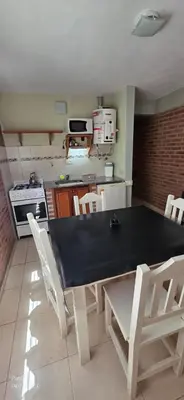 a kitchen with a black table and white chairs at Cabañas Don Lelio in Mina Clavero