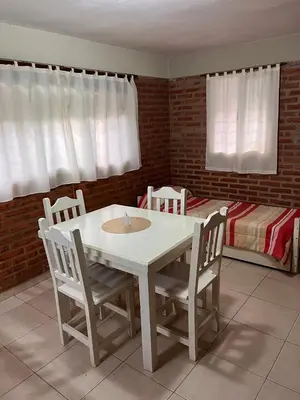 a table and chairs in a room with a bed at Cabañas Don Lelio in Mina Clavero