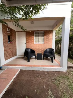 two black chairs sitting on the front porch of a house at Cabañas Don Lelio in Mina Clavero