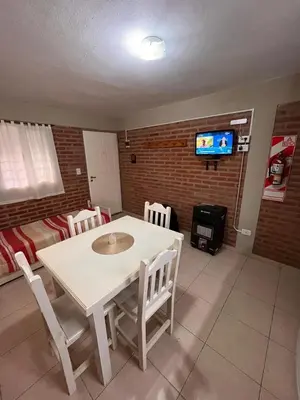 a dining room with a table and chairs and a tv at Cabañas Don Lelio in Mina Clavero