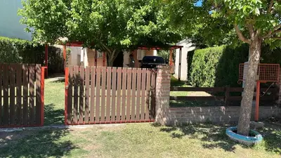 a fence with a tree in front of a house at Cabañas Don Lelio in Mina Clavero