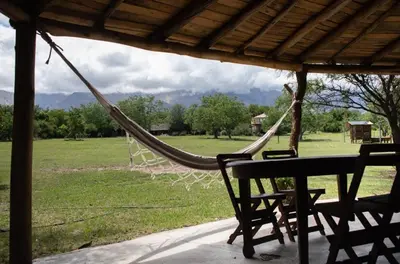 a hammock on a porch with a table and chairs at Cabañas Bendita Tierra- Crespin in Los Molles