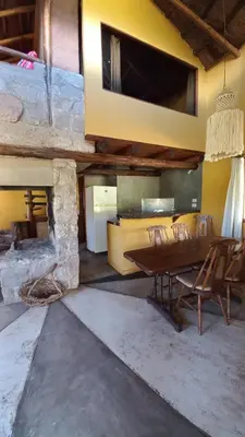a dining room with a table and a stone fireplace at Cabañas Bendita Tierra- Crespin in Los Molles
