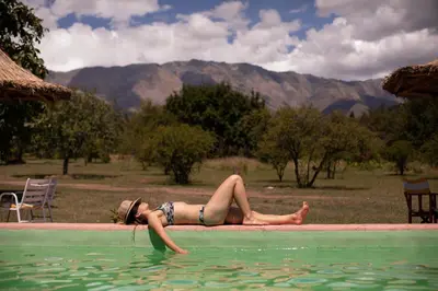 a woman laying in the water in a swimming pool at Cabañas Bendita Tierra - Calandrias in Los Molles