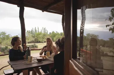 a group of women sitting around a wooden table at Cabañas Bendita Tierra - Calandrias in Los Molles