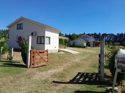 a white house with a wooden gate in front of it at Aire Serrano in Los Reartes