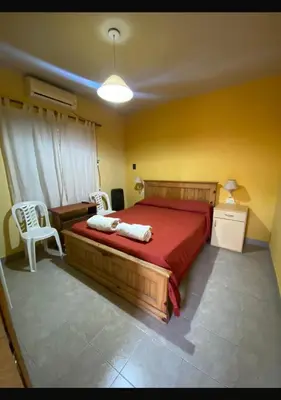 a bedroom with a bed with a red bedspread and two chairs at sukkah in Santa Rosa de Calamuchita