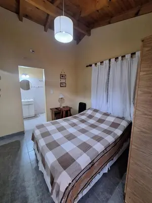 a bedroom with a bed with a checkered blanket at sukkah in Santa Rosa de Calamuchita