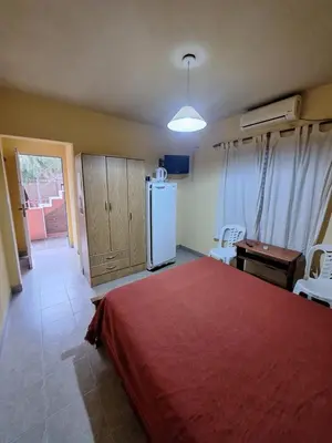 a bedroom with a red bed and a refrigerator at sukkah in Santa Rosa de Calamuchita
