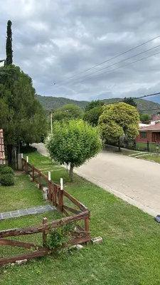 a wooden fence in the grass next to a road at Lodemarta in Villa Carlos Paz