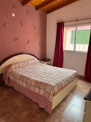 a bedroom with a large bed with a pink wall at Lodemarta in Villa Carlos Paz