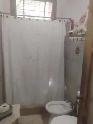 a bathroom with a white toilet and a window at Casa de campo con pileta in Alta Gracia