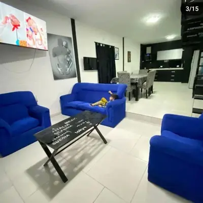 a living room with blue chairs and a baby laying on a couch at Doña LoIa in San Roque