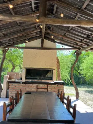a large wooden table with chairs and a fireplace at Cabañas Refugio Lavanda in Villa de Las Rosas