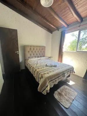 a bedroom with a bed with a blanket and a window at Cabañas Refugio Lavanda in Villa de Las Rosas