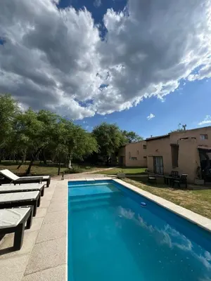 a swimming pool with chaise lounges next to a building at Cabañas Refugio Lavanda in Villa de Las Rosas