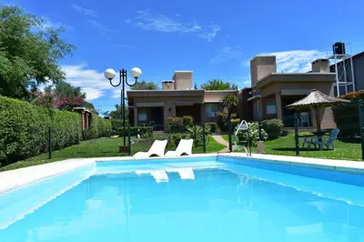 a swimming pool with two chairs and a house at Aparts Solares in San Antonio de Arredondo