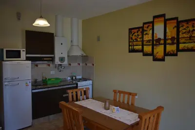 a kitchen with a table and a white refrigerator at Aparts Solares in San Antonio de Arredondo