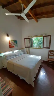a bedroom with a large bed with a ceiling fan at Bungalows Aguas Claras in Villa del Dique