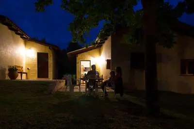 two people sitting at a table in a yard at night at Bungalows Aguas Claras in Villa del Dique