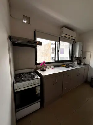 a small kitchen with a stove and a window at depto a 1 cuadra de peatonal, luminoso con pile y cochera in Villa Carlos Paz