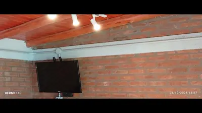 a flat screen tv on a brick wall at Cabañas ojo de aguila in Panaholma