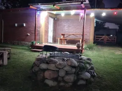 a fire pit in a yard at night with a bench at Cabañas ojo de aguila in Panaholma