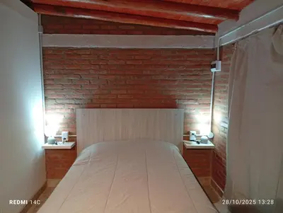 a bed in a room with a brick wall at Cabañas ojo de aguila in Panaholma