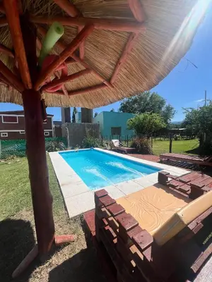 a pool with a wooden umbrella and a swimming pool at Cabañas ojo de aguila in Panaholma