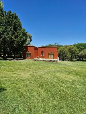 a red house in a field with a grassy field at Rincón del Benítez in Cortaderas