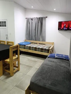 a room with two beds and a tv on the wall at Departamento Sinaí Apart in Santa Rosa de Calamuchita