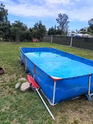 a pool in the grass with a red umbrella next to it at Casa Barrancas del Río Anisacate in Villa Anizacate