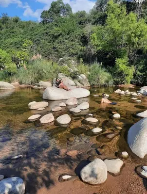 two people swimming on rocks in a river at Las Pircas Apartamentos de Campo in Las Calles