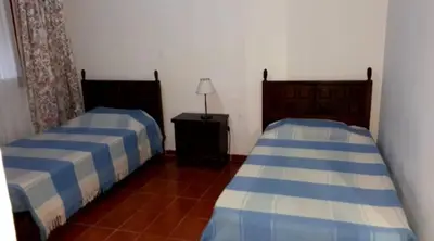 a bedroom with two beds and a table with a lamp at Las Pircas Apartamentos de Campo in Las Calles