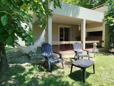 two chairs and a hammock in front of a house at Cabañas El Ceibo in La Bolsa