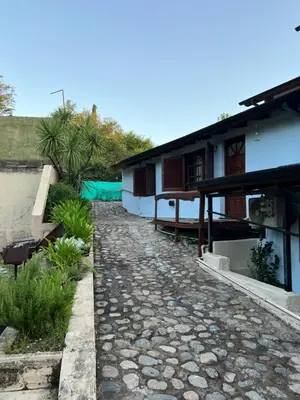 a house with a stone path next to a building at Pequeño chalet con frente al arroyo in Villa General Belgrano