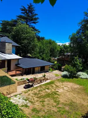 a house with a yard with benches and trees at Pequeño chalet con frente al arroyo in Villa General Belgrano